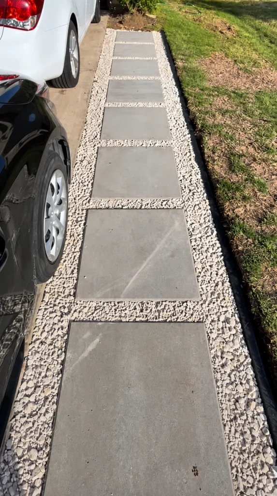 Gray paver strip extension set in gravel along the side of a residential driveway