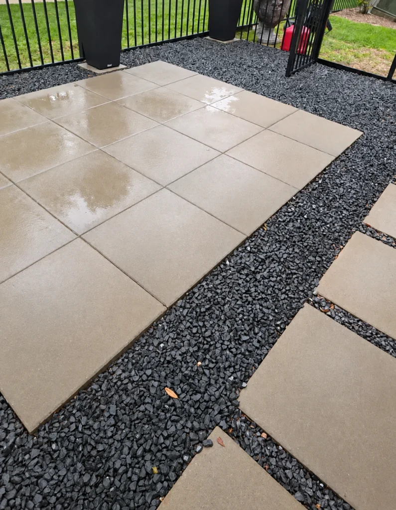 Paver patio with a gravel border, photographed wet after rain to show drainage